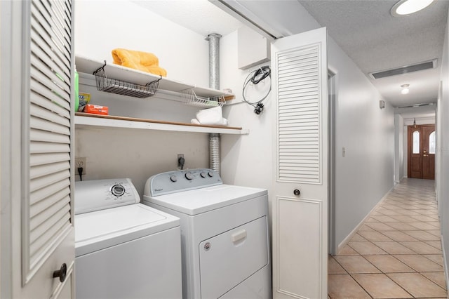 laundry room with light tile patterned floors, washing machine and dryer, and a textured ceiling