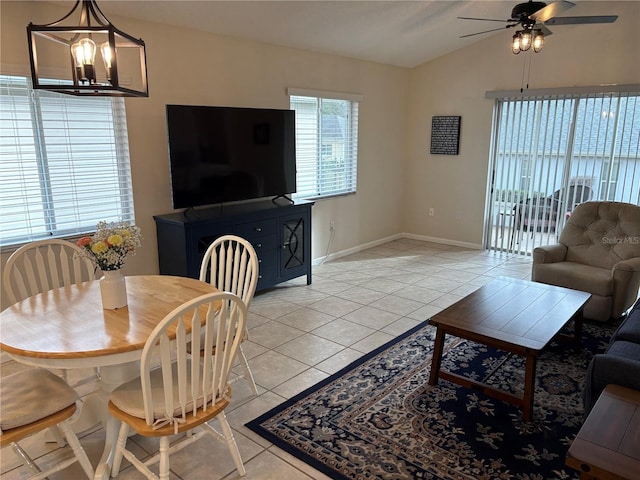 living area with light tile patterned floors, vaulted ceiling, ceiling fan with notable chandelier, and baseboards