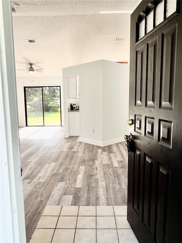 interior space with ceiling fan, light hardwood / wood-style floors, and a textured ceiling