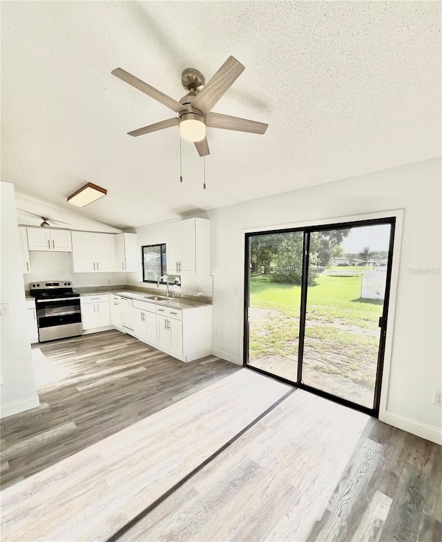 kitchen featuring sink, stainless steel range with electric cooktop, wood-type flooring, a textured ceiling, and white cabinets