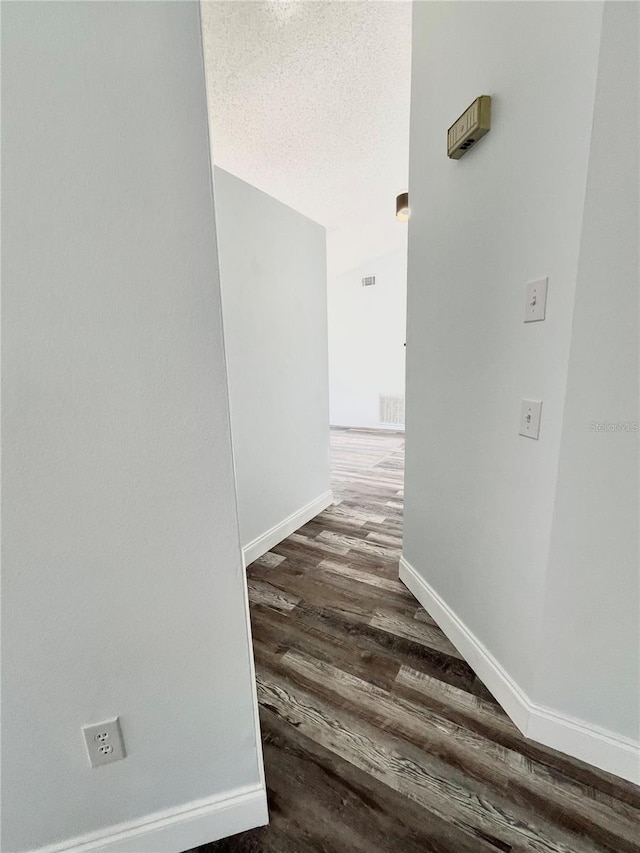 corridor with dark hardwood / wood-style flooring and a textured ceiling