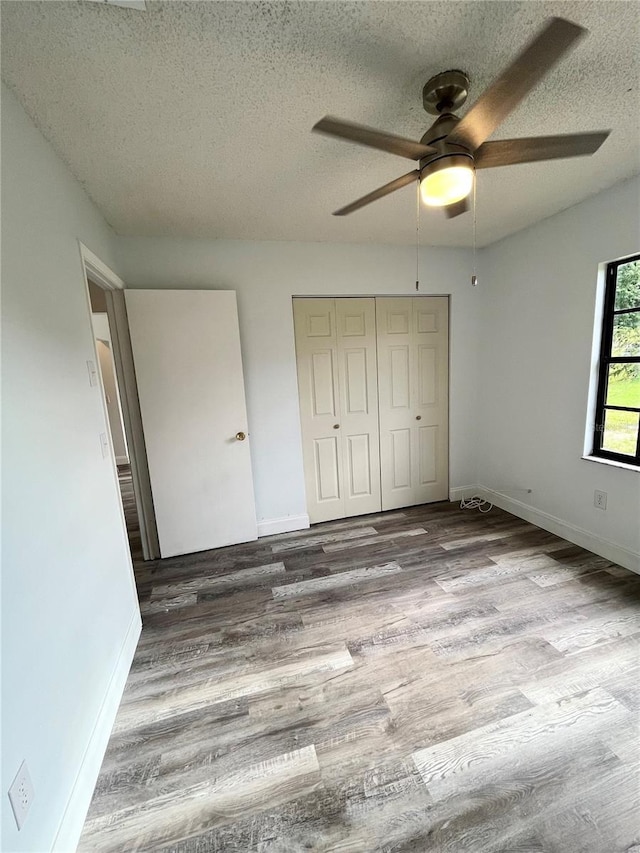 unfurnished bedroom with hardwood / wood-style floors, a closet, a textured ceiling, and ceiling fan