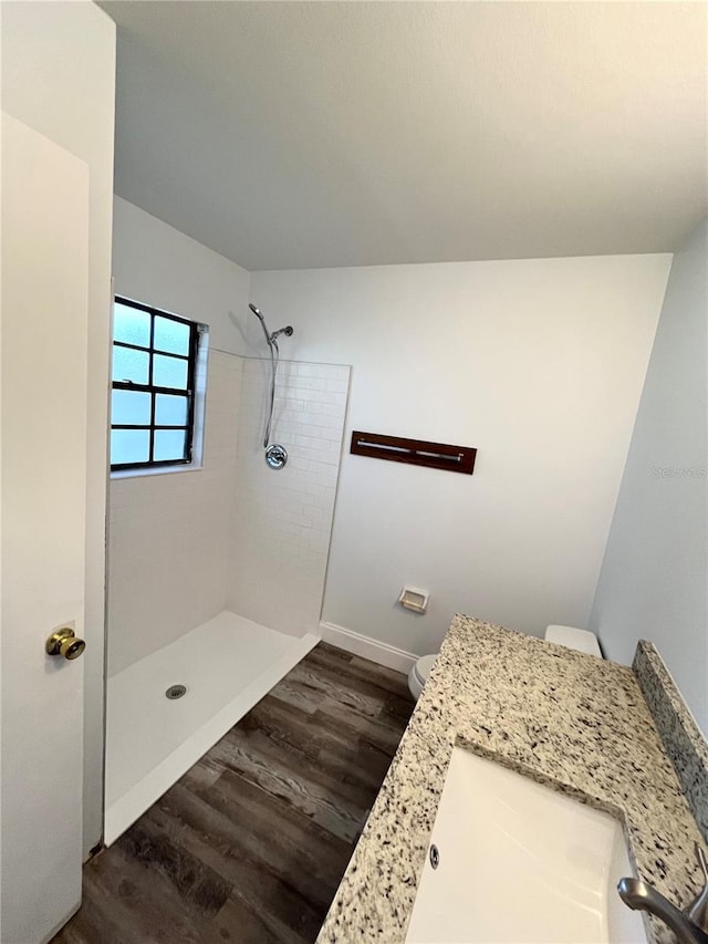 bathroom featuring vanity, toilet, hardwood / wood-style floors, and a tile shower