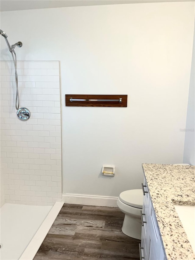 bathroom with vanity, hardwood / wood-style flooring, toilet, and a tile shower