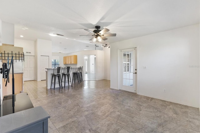 unfurnished living room with lofted ceiling, baseboards, and a ceiling fan