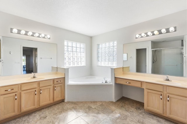 bathroom featuring a stall shower, two vanities, a sink, and a bath