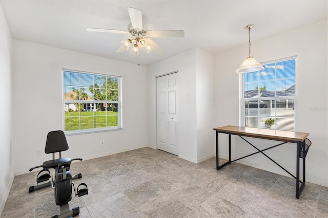 exercise area with a ceiling fan and baseboards