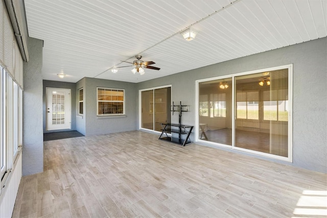 unfurnished sunroom with a ceiling fan and track lighting