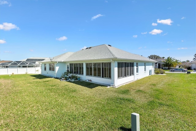 rear view of house featuring a sunroom, a lawn, and fence