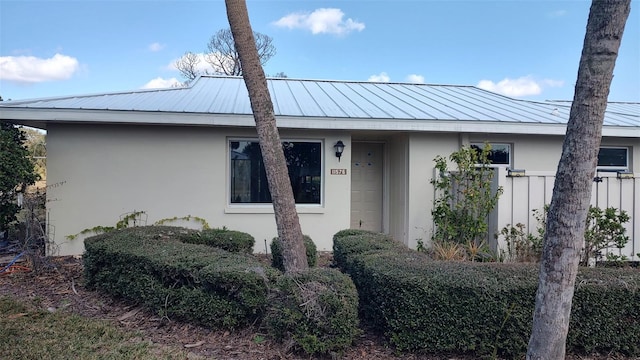 view of front of property featuring a standing seam roof, metal roof, and stucco siding