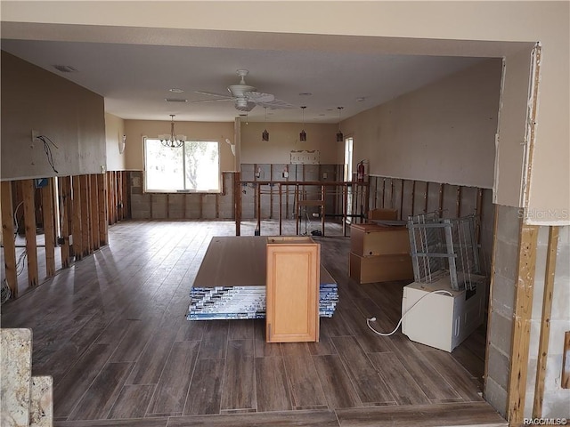 misc room featuring a wainscoted wall, visible vents, dark wood finished floors, and ceiling fan with notable chandelier