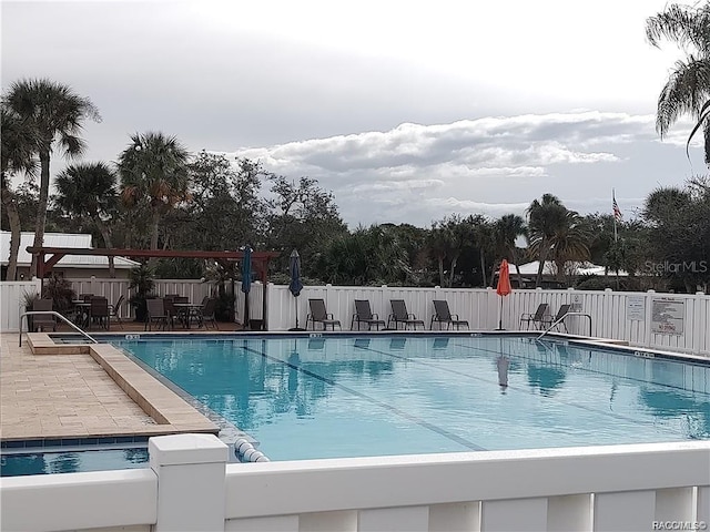 pool with a patio area and fence