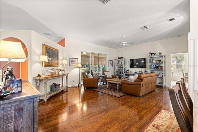 living room with dark hardwood / wood-style flooring, a textured ceiling, and ceiling fan