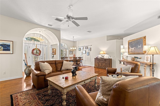 living room with hardwood / wood-style flooring, ceiling fan with notable chandelier, and a textured ceiling