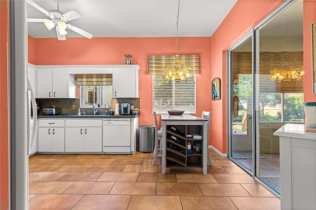 kitchen featuring hanging light fixtures, light tile patterned floors, white cabinets, white appliances, and backsplash