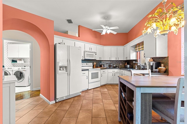 kitchen featuring white appliances, tasteful backsplash, white cabinets, washing machine and clothes dryer, and decorative light fixtures