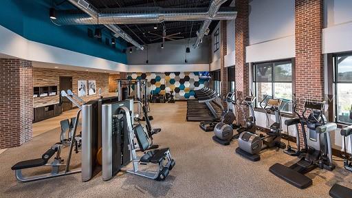 gym with a towering ceiling, brick wall, and carpet floors