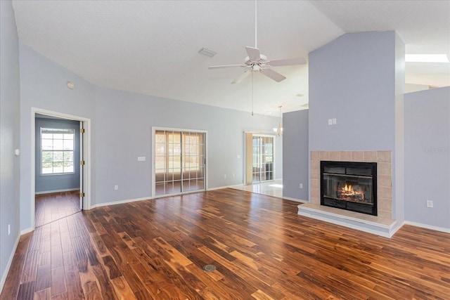 unfurnished living room featuring high vaulted ceiling, a fireplace, wood finished floors, a ceiling fan, and baseboards