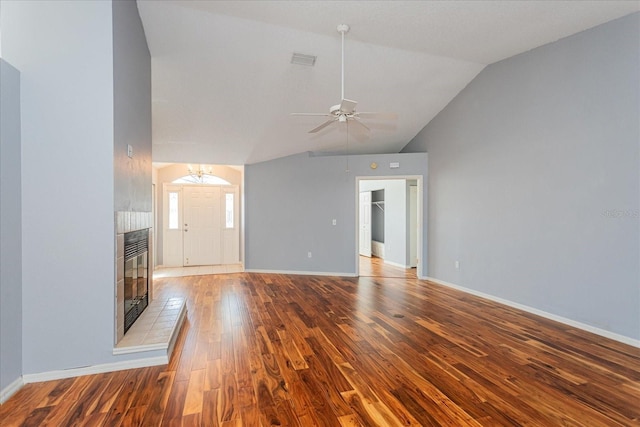 unfurnished living room with ceiling fan with notable chandelier, wood finished floors, visible vents, baseboards, and vaulted ceiling