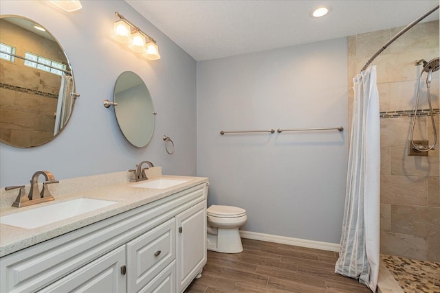 full bath with baseboards, a tile shower, a sink, and wood finished floors