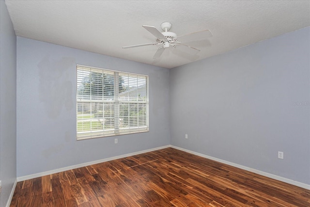 empty room featuring a ceiling fan, dark wood-style flooring, a textured ceiling, and baseboards