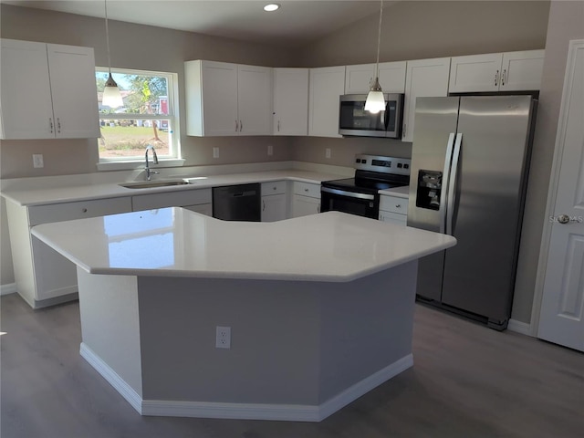 kitchen featuring appliances with stainless steel finishes, light countertops, a sink, and a center island