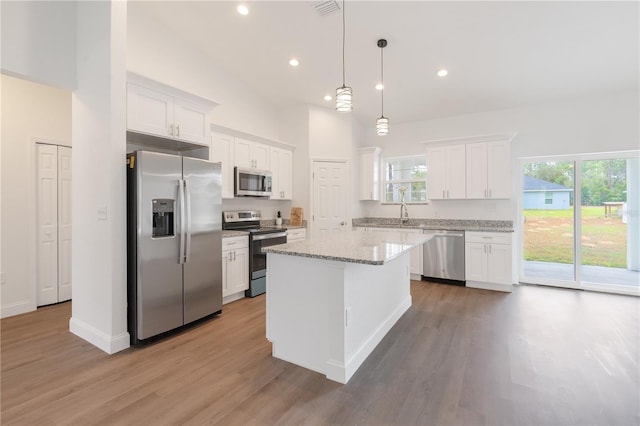 kitchen with pendant lighting, appliances with stainless steel finishes, white cabinets, and a center island