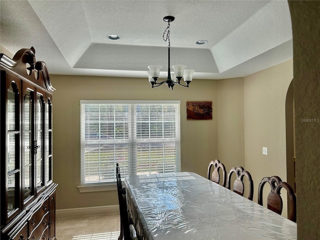 tiled dining area featuring a wealth of natural light, a notable chandelier, a textured ceiling, and a tray ceiling