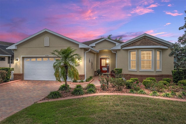 ranch-style home with a garage and a lawn