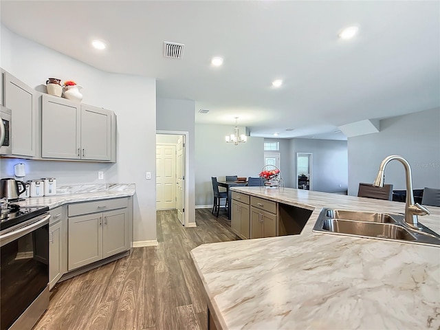 kitchen featuring appliances with stainless steel finishes, gray cabinets, decorative light fixtures, and a sink