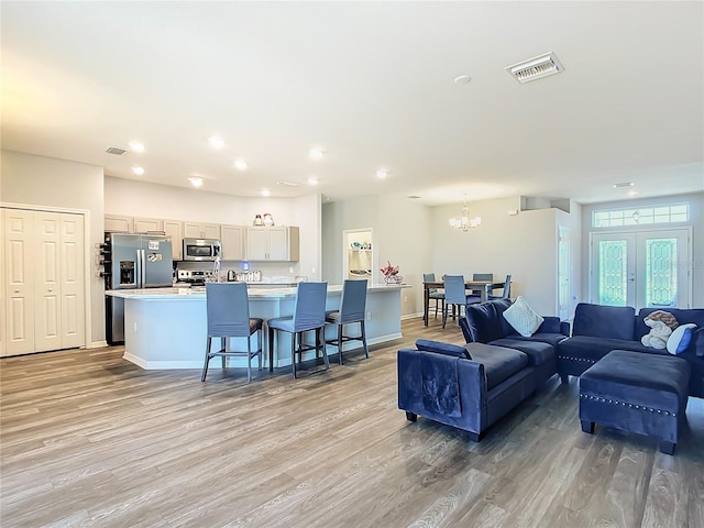 living room with light wood-style flooring, visible vents, and baseboards