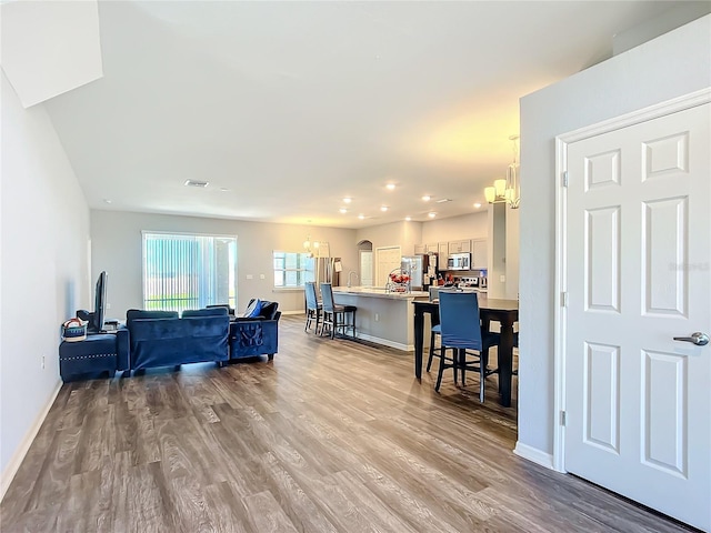 living area with baseboards, light wood finished floors, and a notable chandelier