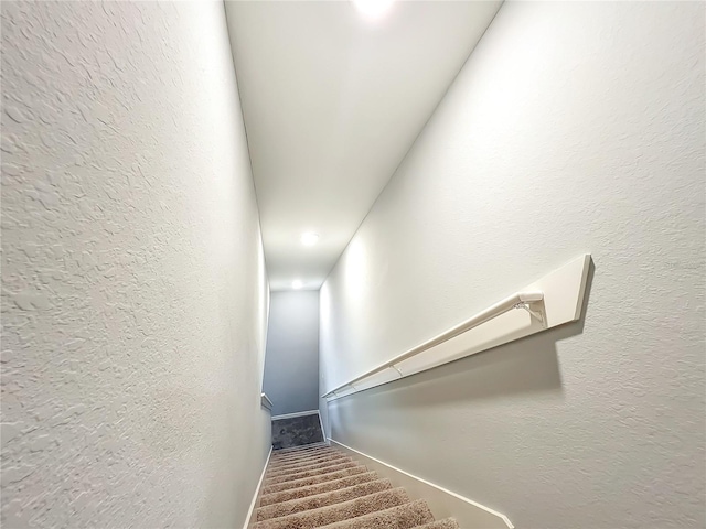 stairway featuring a textured wall and baseboards