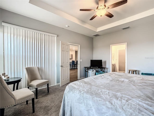 bedroom featuring a ceiling fan, a tray ceiling, visible vents, and carpet flooring