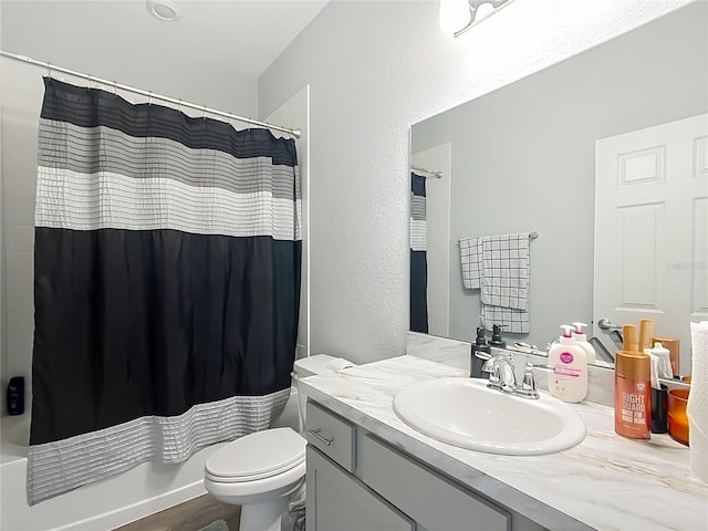 full bath featuring toilet, shower / bath combo with shower curtain, and vanity