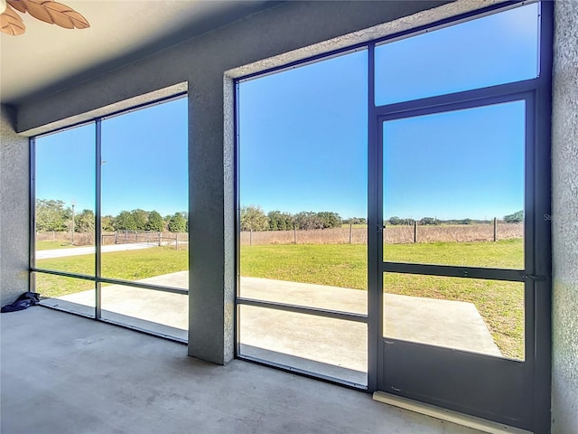 doorway to outside with concrete flooring, a textured wall, and a rural view