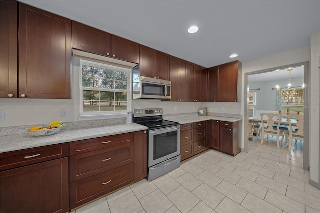 4161 NE 185th Ave, Williston, FL 32696 - kitchen featuring light stone counters, hanging light fixtures, light tile patterned flooring, and appliances with stainless steel finishes