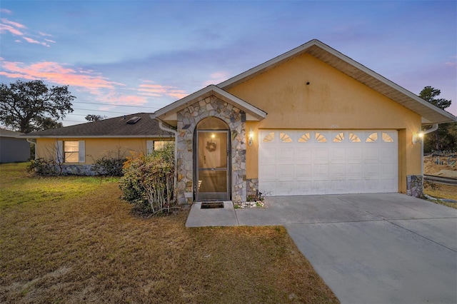 ranch-style home featuring a garage and a lawn