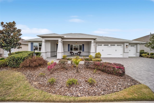 prairie-style home with an attached garage, decorative driveway, and stucco siding