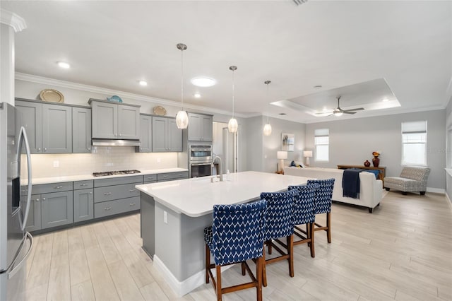 kitchen with open floor plan, hanging light fixtures, a kitchen island with sink, stainless steel appliances, and a kitchen bar