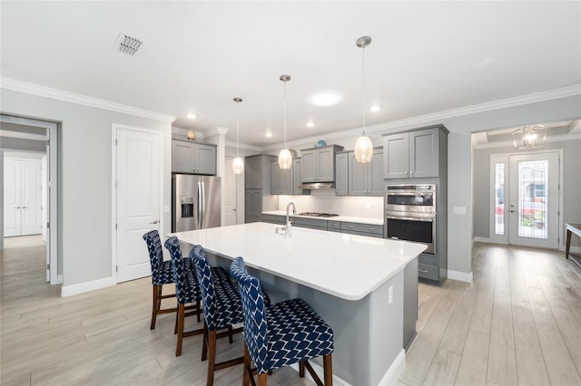 kitchen featuring a breakfast bar, visible vents, light countertops, appliances with stainless steel finishes, and decorative light fixtures