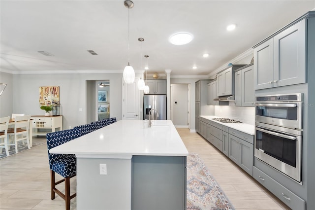 kitchen with a large island, appliances with stainless steel finishes, a breakfast bar area, gray cabinets, and light countertops