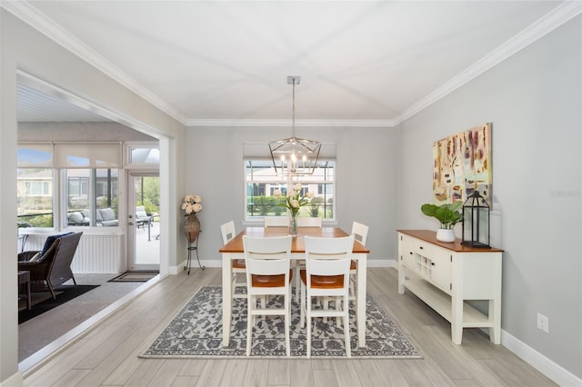 dining space with light wood-style floors, a chandelier, ornamental molding, and baseboards