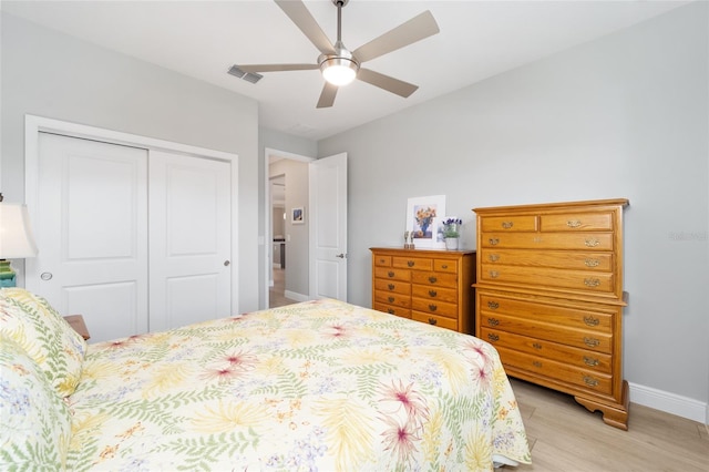 bedroom featuring light wood finished floors, a closet, visible vents, a ceiling fan, and baseboards