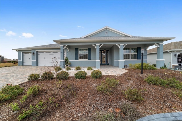 view of front of property with covered porch, decorative driveway, an attached garage, and stucco siding