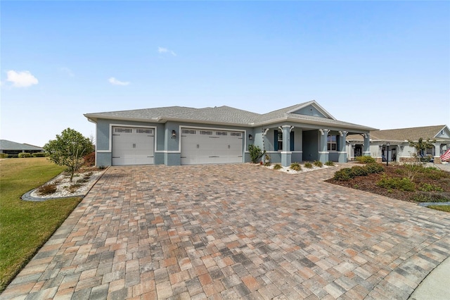 view of front facade with decorative driveway, an attached garage, and stucco siding