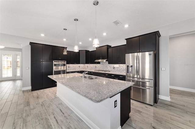 kitchen with decorative light fixtures, visible vents, appliances with stainless steel finishes, a sink, and an island with sink