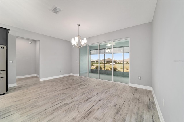 spare room with light wood-style floors, baseboards, visible vents, and a chandelier