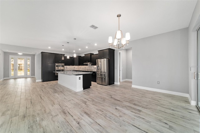 kitchen with a center island with sink, visible vents, open floor plan, hanging light fixtures, and stainless steel appliances