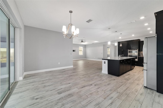 kitchen with a center island with sink, visible vents, open floor plan, and decorative light fixtures